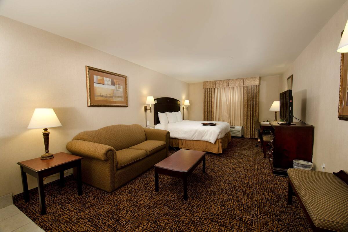 Ein Hotelzimmer mit Bett, einer Couch, einem kleinen Tisch, einem Fernseher und einer Lampe.