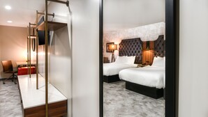 Habitación de hotel con diseño moderno, que incluye una cama grande con cabecera capitonada, un escritorio con silla y un armario.
