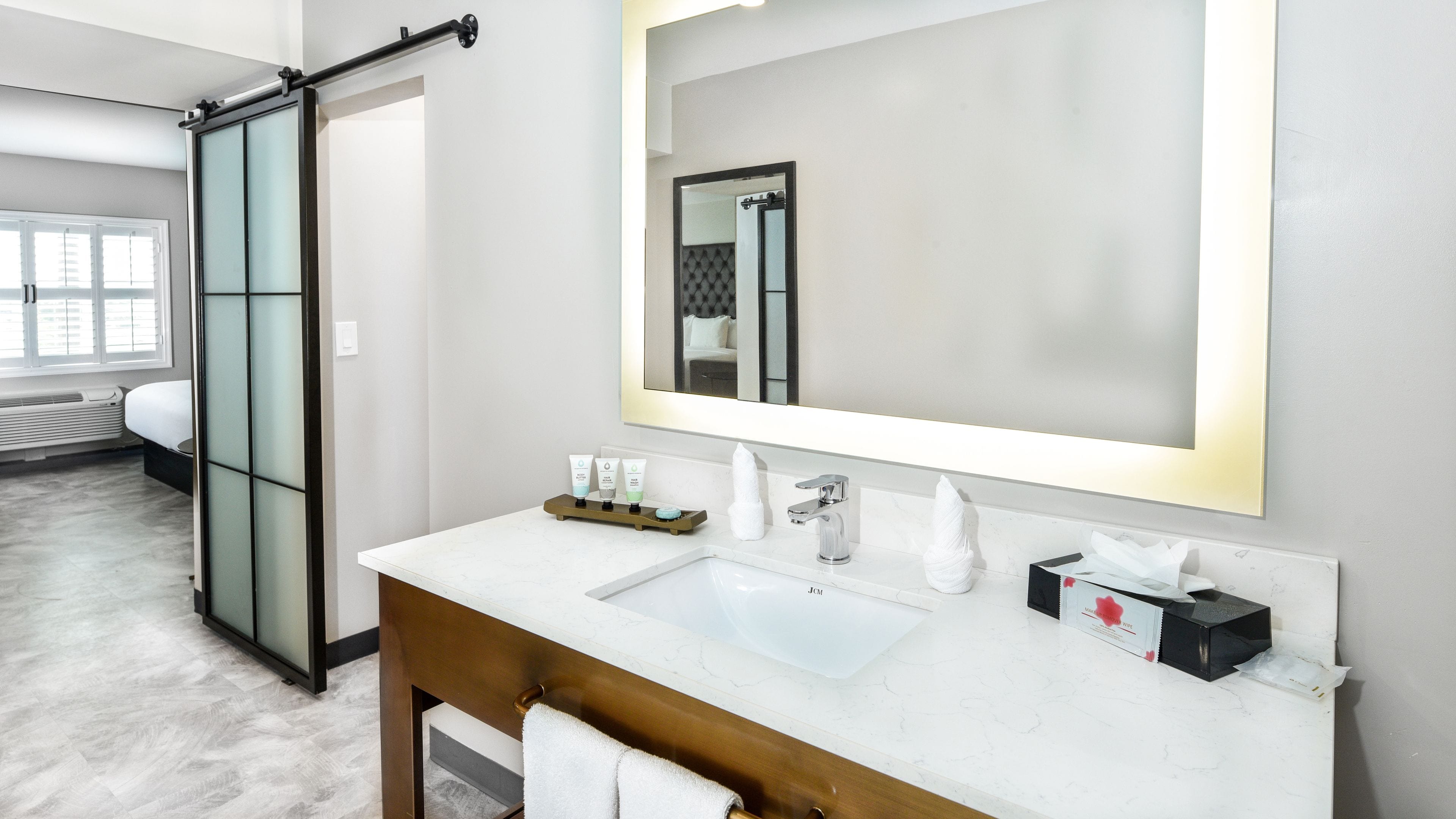 A modern bathroom with a large mirror, two sinks, and a towel rack.