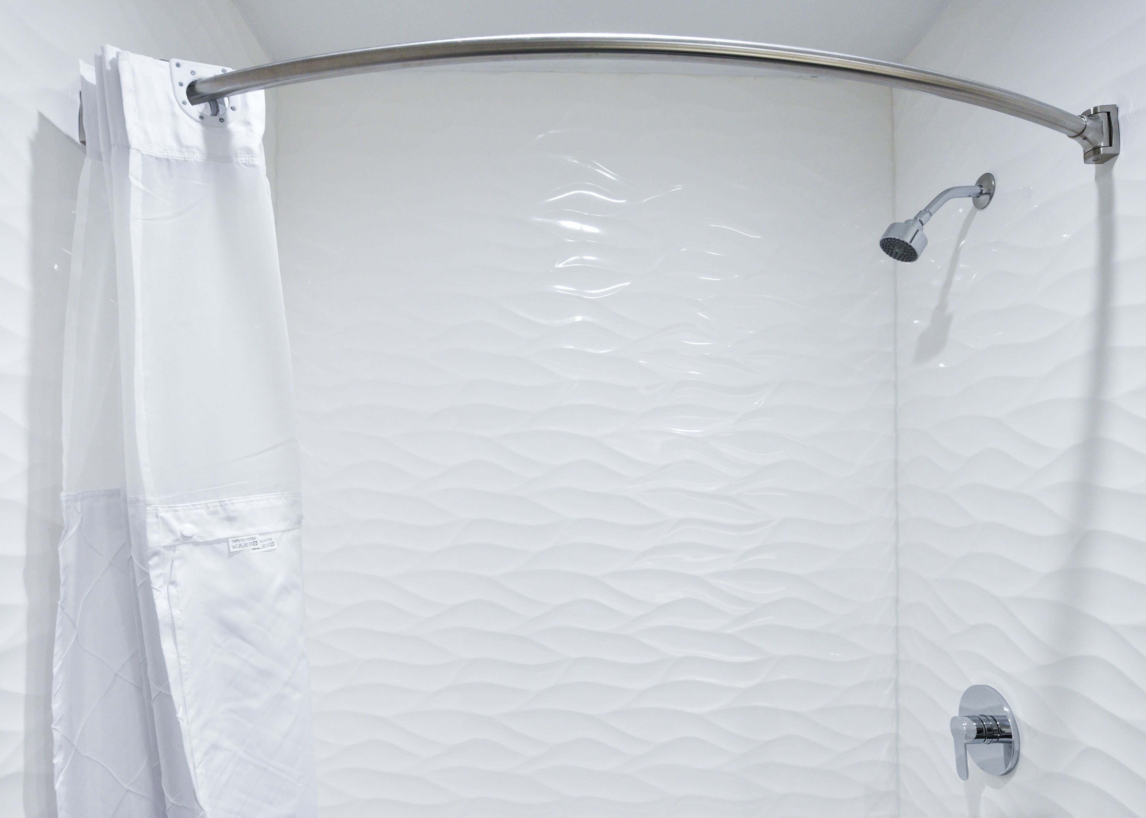 A shower with a curved glass door and a chrome showerhead.