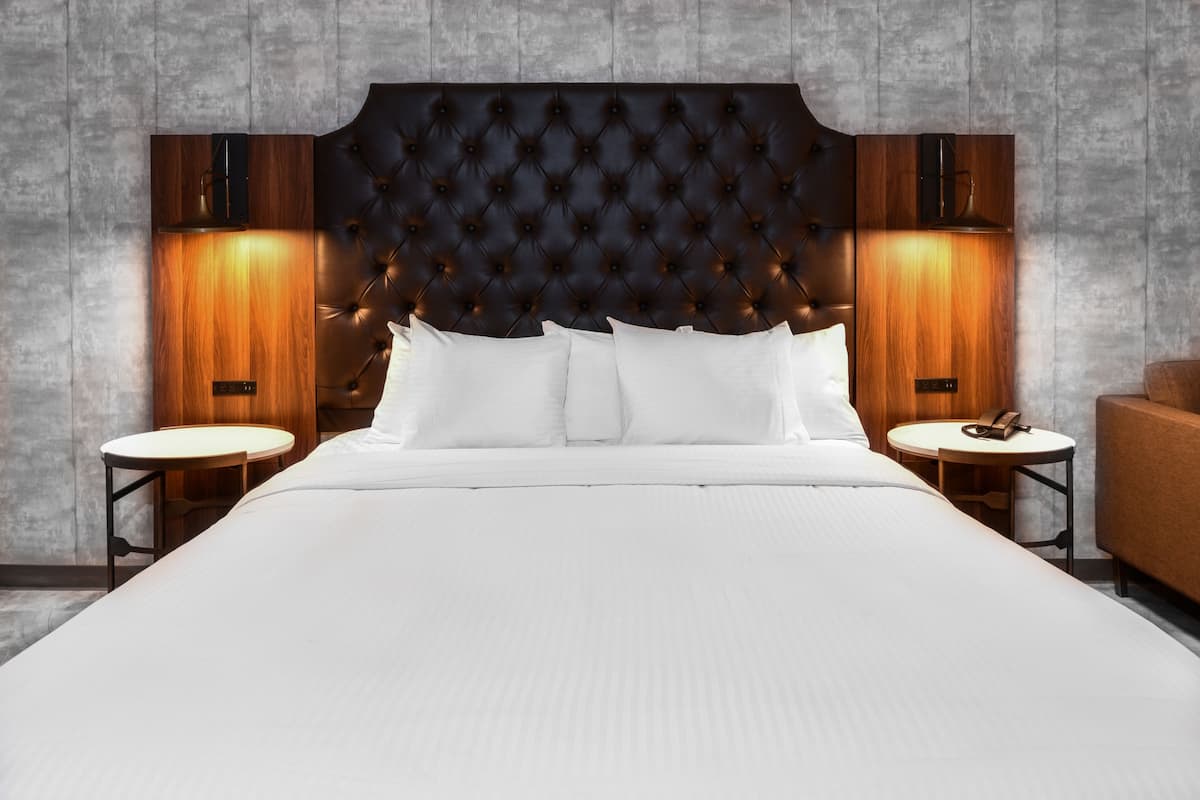 A large bed with a tufted headboard, two bedside tables, and a wooden nightstand.