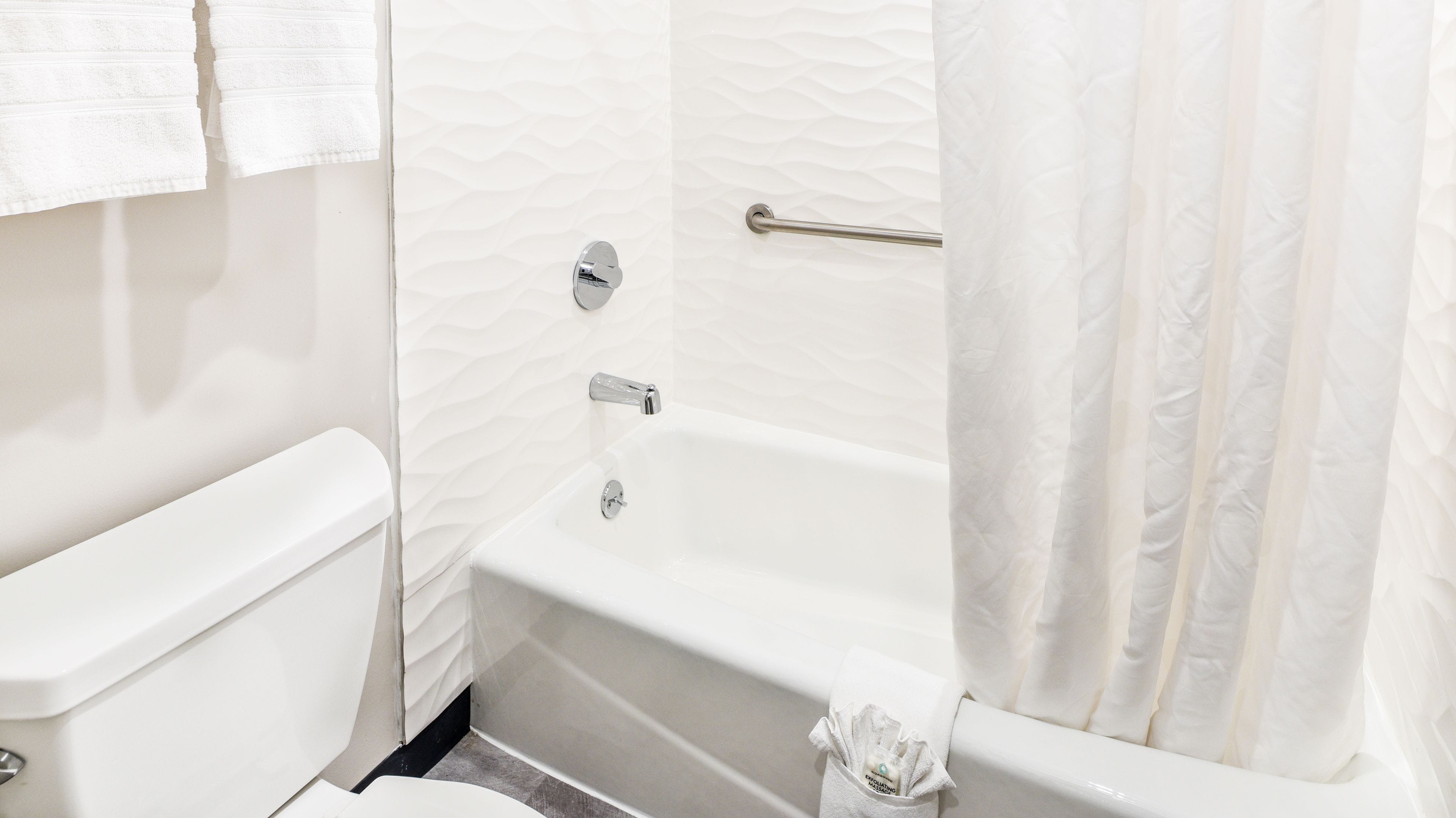 A bathroom with a white bathtub, a toilet, and a shower curtain.