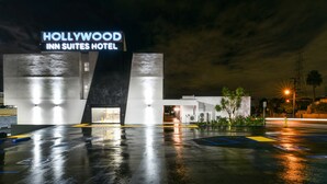 Hotel Hollywood Inn Suites, con un diseño moderno, una entrada visible y un estacionamiento con espacios delimitados.