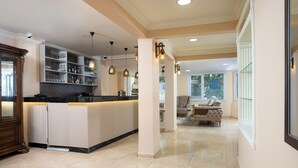 Una cocina amplia con una isla central, estantes empotrados, iluminación colgante y vistas a una sala de estar.