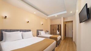 Habitación de hotel con dos camas, televisión, armario y baño.