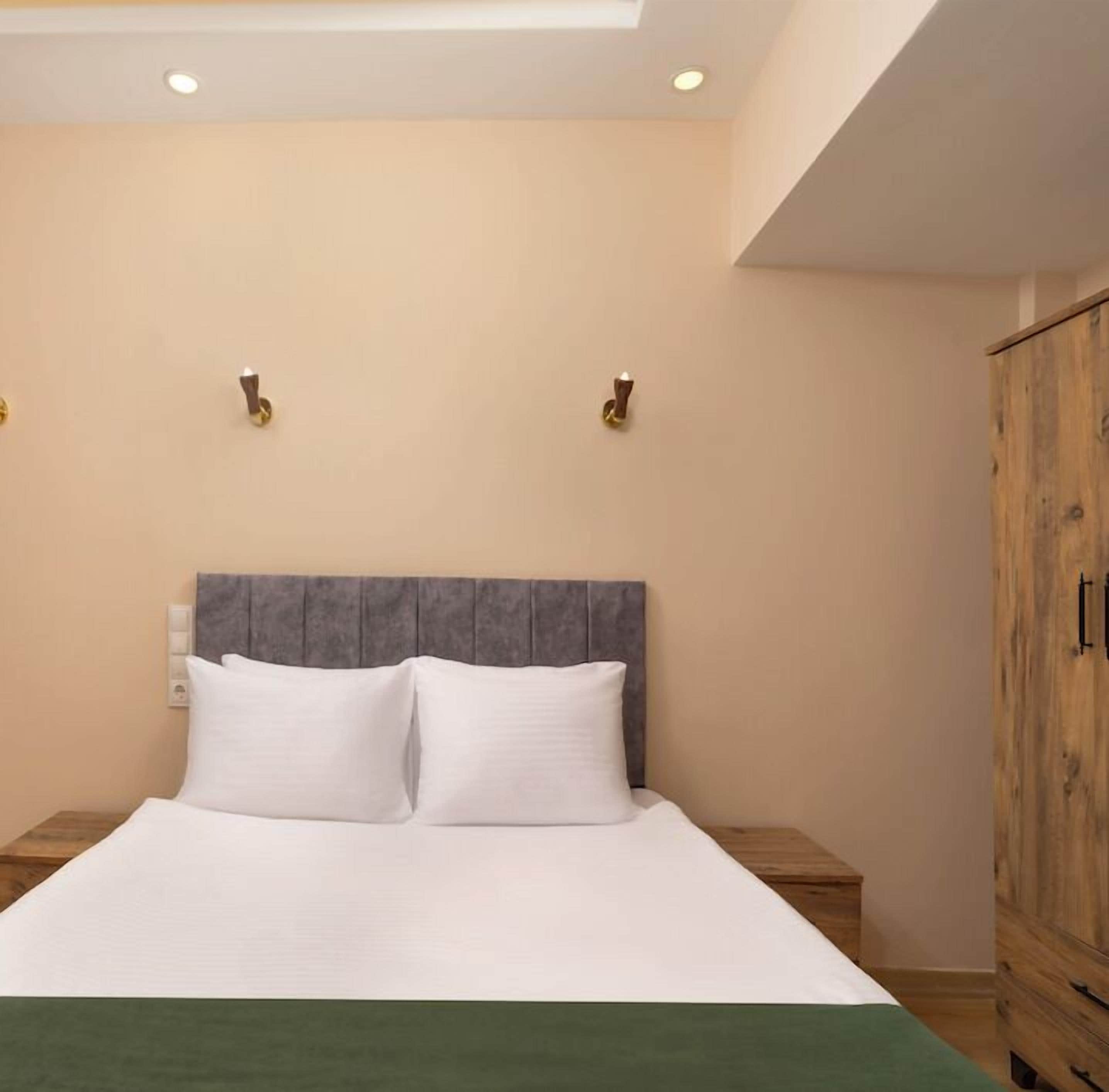 A bed with a grey headboard, two bedside tables, and a wooden wardrobe.