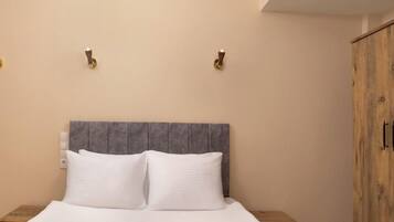 A bed with a grey headboard, two bedside tables, and a wooden wardrobe.