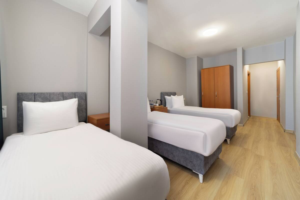 Ein Hotelzimmer mit zwei Betten, einem Kleiderschrank, einem Nachttisch und einem begehbaren Kleiderschrank.
