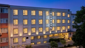 Un hotel de varios pisos con un llamativo letrero 'ULB HOTEL', ventanas amplias y una fachada bien iluminada.