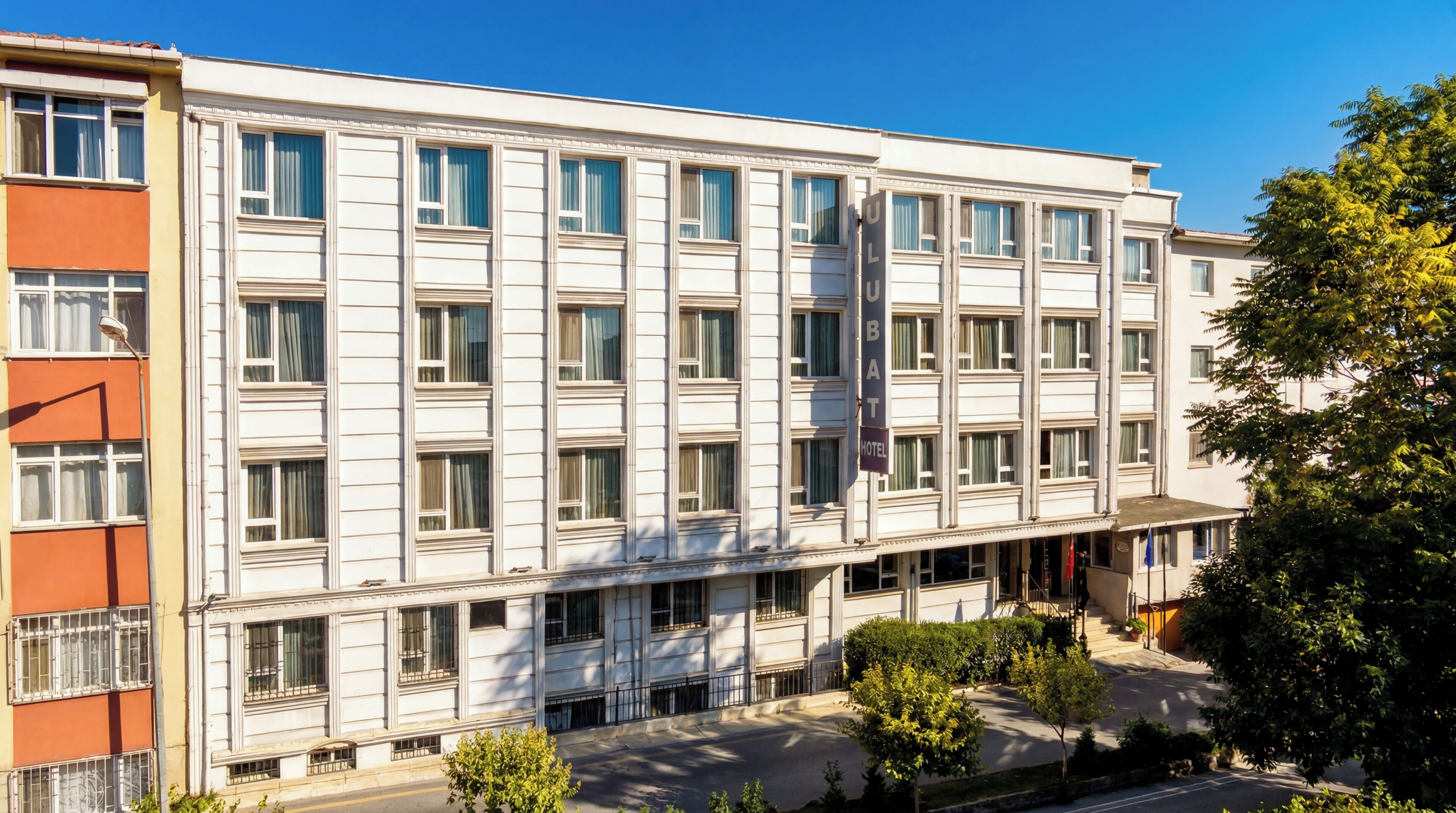 Un hôtel à plusieurs étages, doté d’une façade symétrique, de grandes fenêtres et d’une entrée centrale.