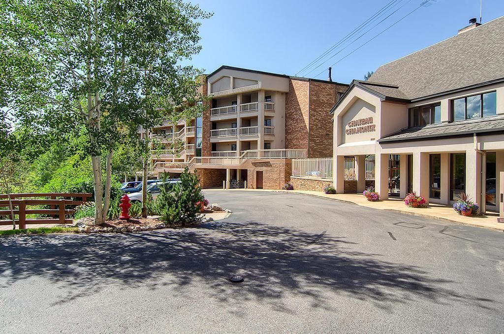 A hotel with a multi-story building, a parking lot, and a fire hydrant.