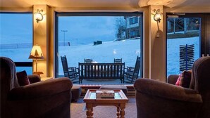 A cozy room with a large window overlooking a snowy landscape, furnished with a sofa, chairs, and a small table. - Chateau Chamonix - Cx326 Condominium (Steamboat Springs)