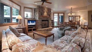 A spacious living room with a stone fireplace, comfortable seating, and a ceiling fan. - Chateau Chamonix - Cx326 Condominium (Steamboat Springs)