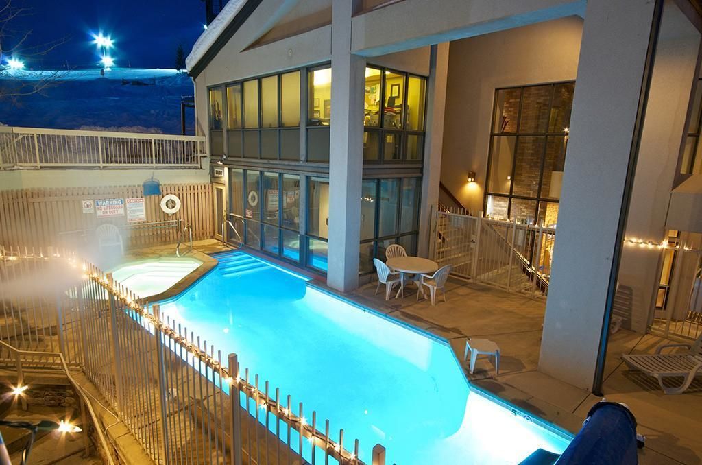 An indoor swimming pool with a fenced area, lounge chairs, and a covered seating area with tables.