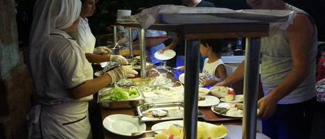 A food stall with various dishes and a person serving food.