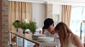 Una mesa de buffet con diferentes alimentos, un recipiente metálico grande y una cesta de mimbre.