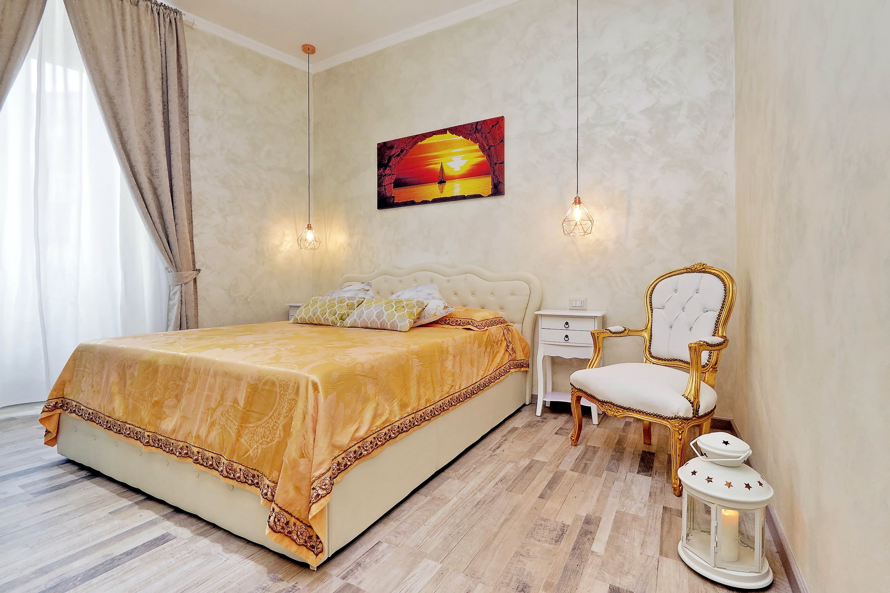 Une chambre à coucher avec un grand lit, une table de chevet, une chaise et un tableau accroché au mur.