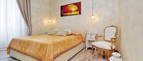 Une chambre à coucher avec un grand lit, une table de chevet, une chaise et un tableau accroché au mur.