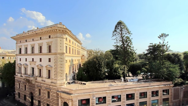 Un edificio histórico con arquitectura clásica, que presenta un patio central y una extensión moderna con señalización comercial.