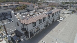 An aerial view of a building with a flat roof, multiple windows, and a parking lot. - Just Finished and Furnished!  Spacious Luxury Condo 326 Stimson Ave, Pismo Beach (Pismo Beach)