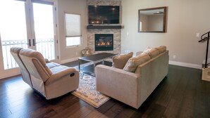 A living room with a fireplace, a ceiling fan, and a large mirror. - Just Finished and Furnished!  Spacious Luxury Condo 326 Stimson Ave, Pismo Beach (Pismo Beach)