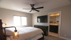 A bedroom with a bed, bedside lamp, ceiling fan, and a TV on the wall. - Just Finished and Furnished!  Spacious Luxury Condo 326 Stimson Ave, Pismo Beach (Pismo Beach)