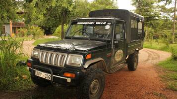 A black SUV with a camper trailer parked on a dirt path.