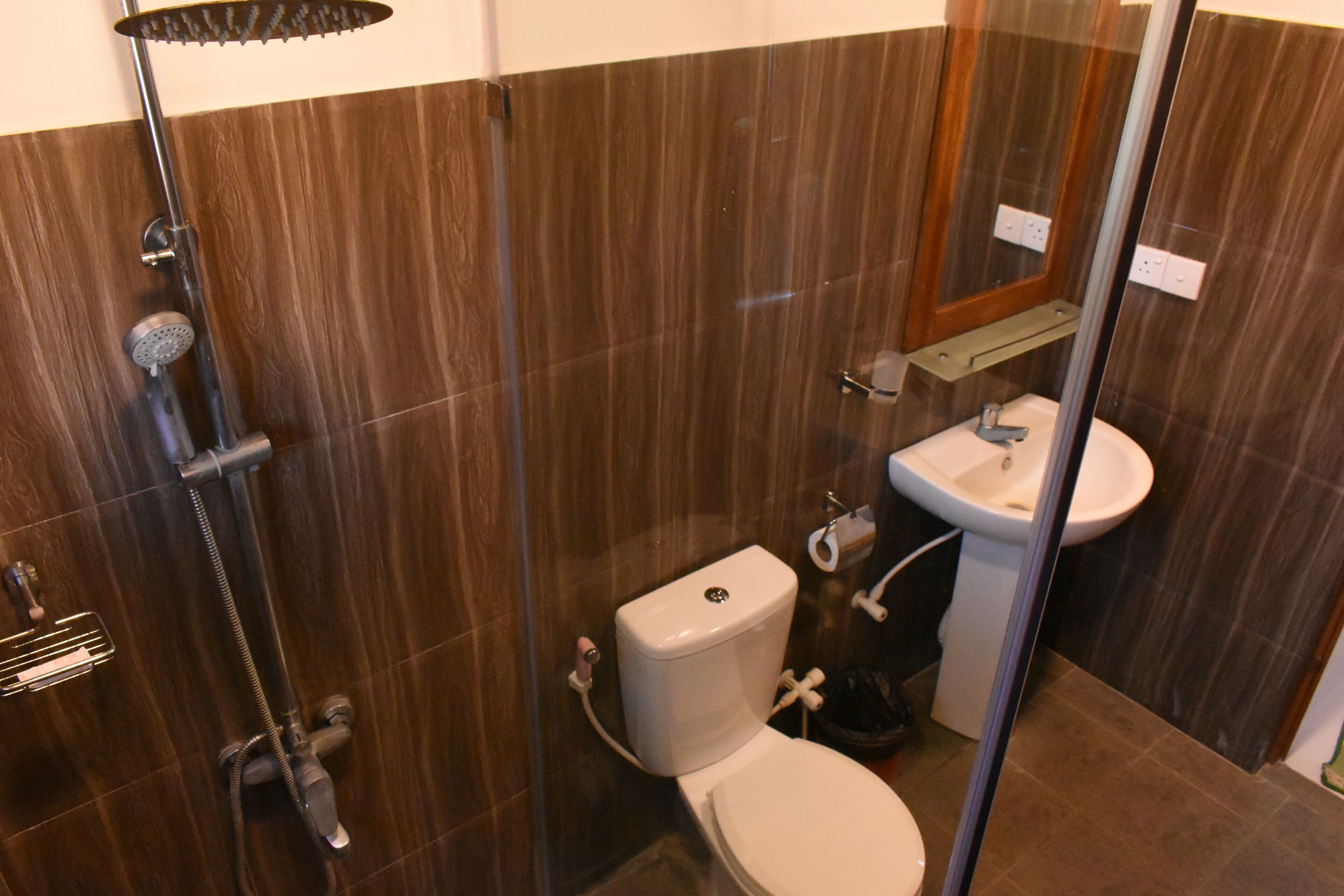 Un baño con ducha de vidrio, inodoro y lavamanos.
