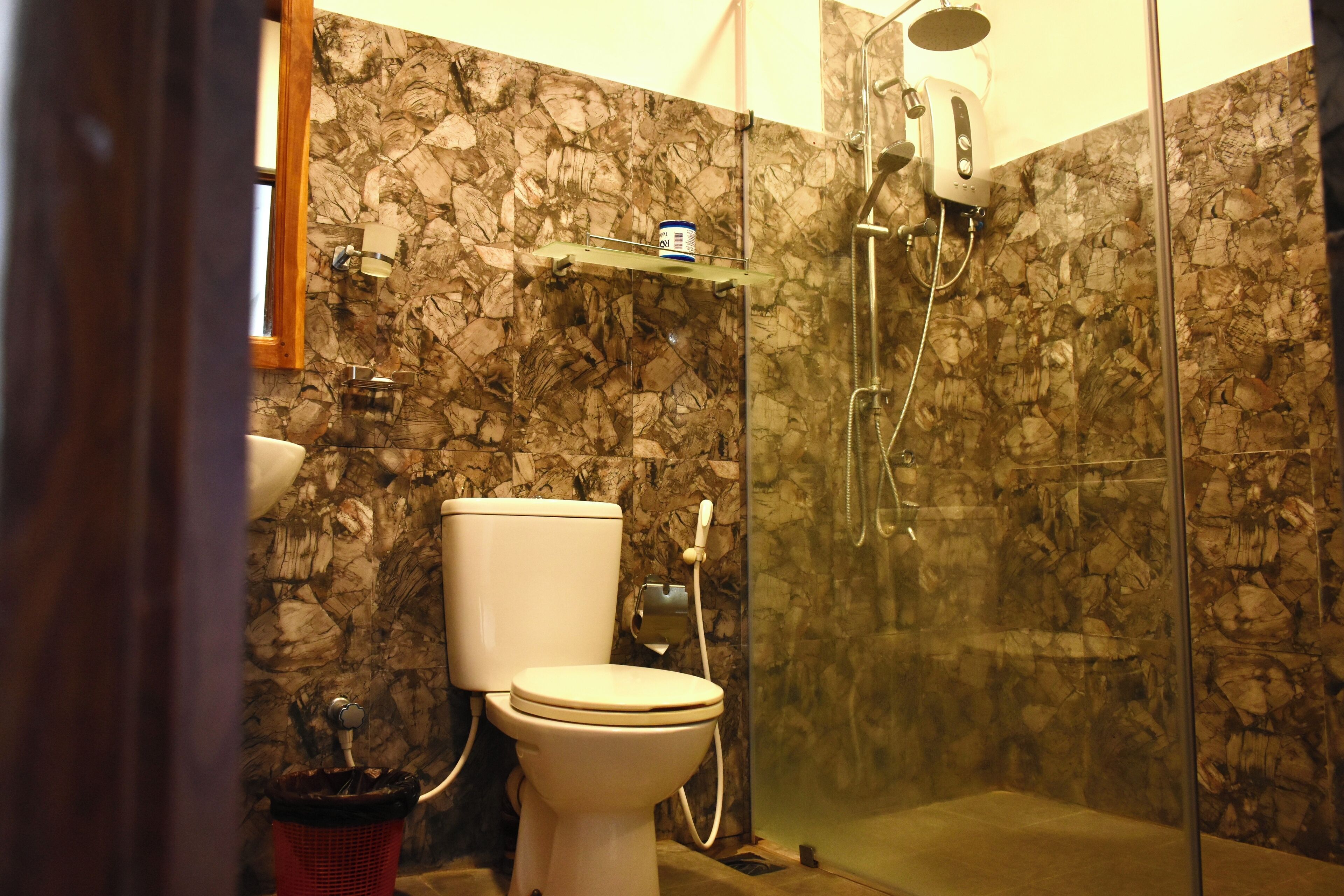 A bathroom with a toilet, shower, and marble walls.