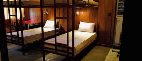A room with bunk beds, a desk, and a chair.