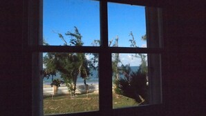 Una ventana con vista a la playa y árboles.