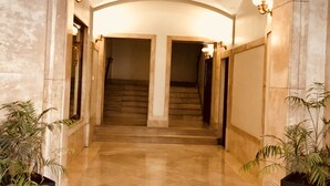 A hallway with a marble floor, a staircase, and two potted plants. - 4 bedrooms appartmts (València)