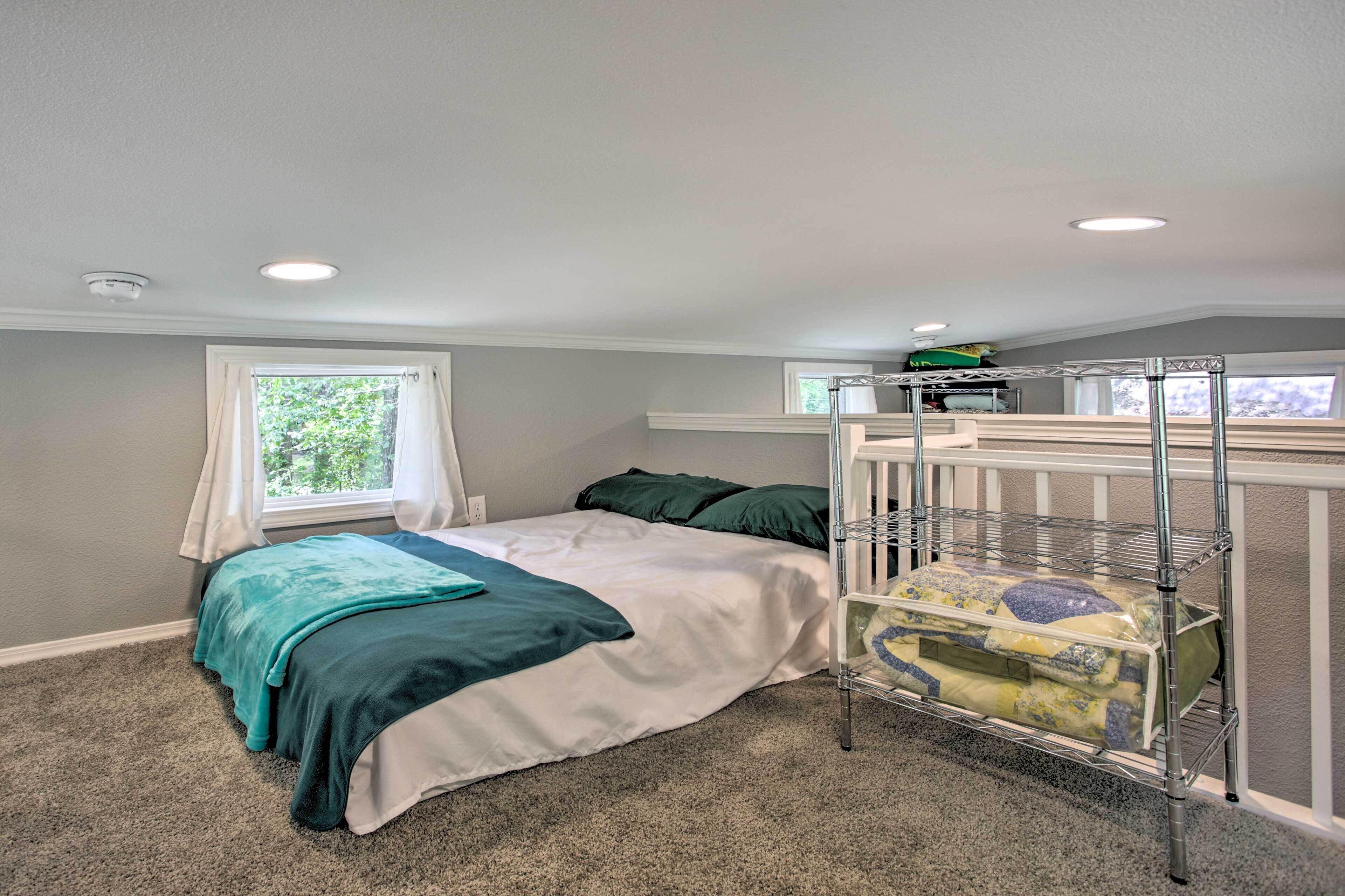 A bedroom with a bunk bed, a window with curtains, a metal shelf with laundry, and a ceiling light.