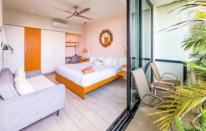 Ein modernes Hotelzimmer mit Bett, Sofa, Schreibtisch und einem Balkon mit Pflanzen.