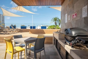 Eine Terrass mit Grill, Sitzgelegenheiten und Blick aufs Meer.