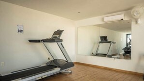 A room with a treadmill, a large mirror, and an air conditioning unit.