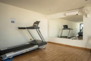 A room with a treadmill, a large mirror, and an air conditioning unit.