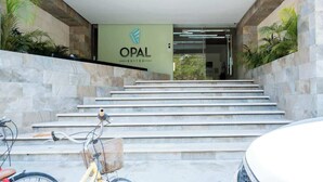 A hotel entrance with a sign reading 'OPAL SUITES,' a staircase, and a bicycle parked outside.