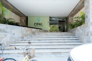 A hotel entrance with a sign reading 'OPAL SUITES,' a staircase, and a bicycle parked outside.