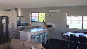 A modern kitchen with a central island, bar stools, and a dining area with chairs.