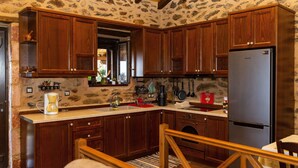 A kitchen with wooden cabinets, a stainless steel refrigerator, and a coffee maker. - Mystras Village House (Sparta)