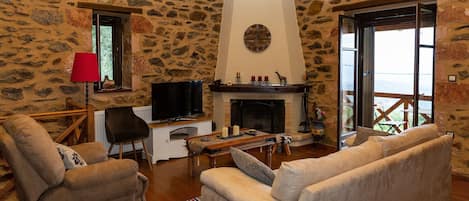 A stone-walled living room with a fireplace, a television, and comfortable seating.