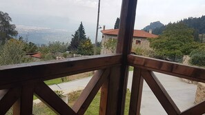 A balcony with a wooden railing overlooking a coastal landscape with houses and trees. - Mystras Village House (Sparta)
