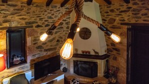 A rustic interior with exposed stone walls, a fireplace, and a wooden ceiling. - Mystras Village House (Sparta)