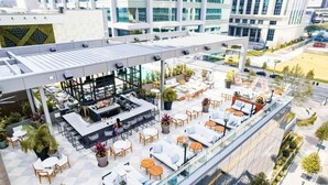 Eine Dachterrasse mit Außenbestuhlung, umgeben von Topfpflanzen und moderner Architektur.