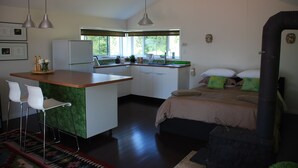 Une cuisine moderne avec un îlot central, des tabourets de bar blancs et un lit agrémenté d’oreillers verts.
