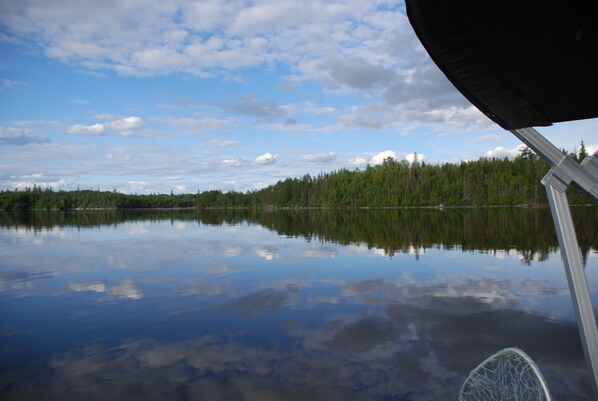 A calm lake with a forested shoreline and a boat's cabin structure. - Cozy & Pet-friendly Lakefront Cottage (Guérin)