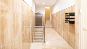 Um corredor moderno com corrimão de metal, escada e um móvel de armazenamento fixado na parede.
