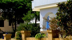 Un edificio moderno con fachada blanca, contraventanas azules y base de piedra.