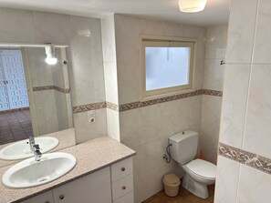 Une salle de bain avec deux lavabos, des toilettes et une fenêtre.